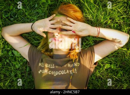 Une jeune femme roumaines couvrant les yeux en étant allongée sur la pelouse à Lasi, Roumanie Banque D'Images