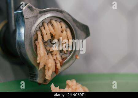 Viande fraîche hachée dans les rouleaux du moulin à viande. Produit animal. Usine de production et de consommation de viande de porc, d'agneau, de poussin, de bœuf. Cuisine ingre Banque D'Images