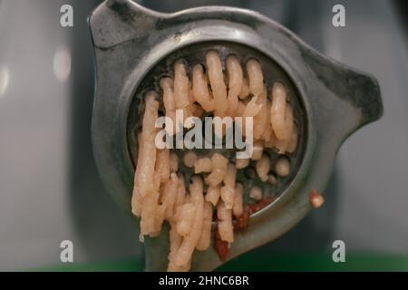 Viande fraîche hachée dans les rouleaux du moulin à viande. Produit animal. Usine de production et de consommation de viande de porc, d'agneau, de poussin, de bœuf. Cuisine ingre Banque D'Images