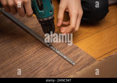Tournevis à main mâle vissant les vis pour coller le détail de la pièce à la carte. Assemblage de meubles à la maison. Copier l'espace. Utilisation de Banque D'Images