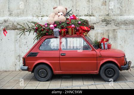 Petite voiture vintage avec arbre de Noël et un ours en peluche sur le toit Banque D'Images