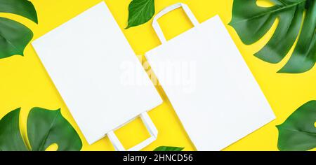 Sacs en papier écologiques sur fond jaune.Sac à provisions en papier recyclé avec feuilles vertes.ensemble de sacs en papier jetables pour les aliments à emporter, g Banque D'Images