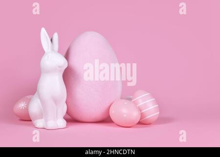 Sculpture de lapin blanc avec œufs de pâques sur fond rose avec espace de copie Banque D'Images