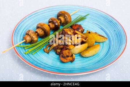 Différents champignons savoureux friture avec des pommes de terre à l'assiette à la table Banque D'Images