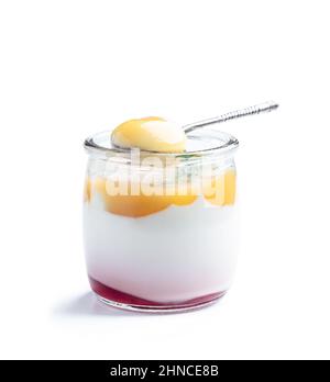 Yogourt blanc crémeux avec purée de fruits jaunes dans un petit pot isolé sur blanc Banque D'Images