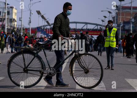 Katmandou, ne, Népal. 16th févr. 2022. Un homme porte son cycle à travers une traversée de zèbre lors d'une protestation contre la subvention du MCC du gouvernement américain proposée pour le Népal, à Katmandou, Népal, le 16 février 2022. (Image de crédit : © Aryan Dhimal/ZUMA Press Wire) Banque D'Images