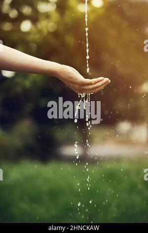 L'eau est la force motrice de toute nature. Coupe courte d'eau sur une main de femme à l'extérieur. Banque D'Images