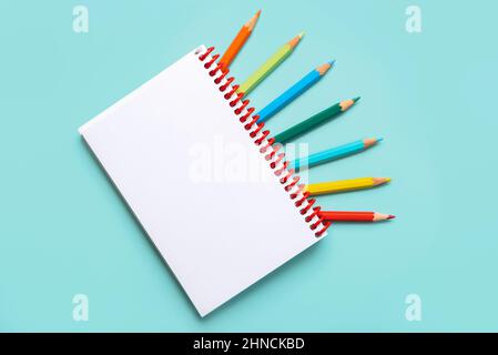 palette arc-en-ciel de crayons de couleur avec un cahier à spirale sur fond  jaune, maquette, mise à plat. rentrée scolaire, recrutement étudiant,  artiste, cours de dessin. espace de copie. papeterie pour la