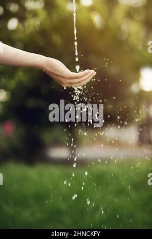 L'eau est la vie, ne la gaspillez pas. Coupe courte d'eau sur une main de femme à l'extérieur. Banque D'Images