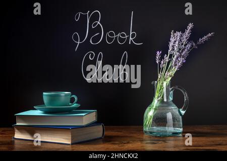 Concept de Club de livre. Une pile de livres et une tasse de café sur un bureau avec du lettrage à la craie et des fleurs de lavande Banque D'Images