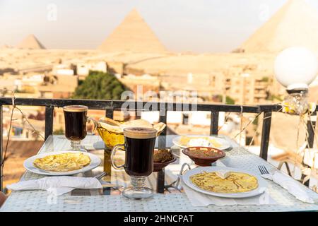 Petit déjeuner du voyageur. Une table dans un restaurant en plein air avec une vue magnifique sur les grandes pyramides de Gizeh. Le Caire. Égypte. Dîner romantique Banque D'Images