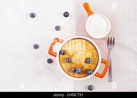 Cocotte de fromage cottage sur un plat de cuisson sur fond clair. Petit déjeuner sain. Vue de dessus Banque D'Images