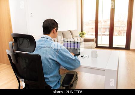 Vue arrière d'un homme d'affaires méconnu travaillant sur son ordinateur portable au bureau à la maison Banque D'Images