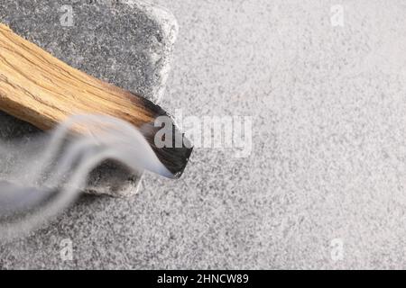 Palo Santo Stick encens brûlant sur pierre grise. Gros plan. Style minimaliste. Nettoyage rituel, méditation, aromathérapie. Pratiques spirituelles péruviennes. COP Banque D'Images