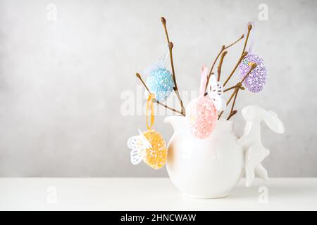 Intérieur de la maison avec décor de pâques.Vase avec branches de saule avec œufs de Pâques et lapin sur table blanche et arrière-plan avec espace de copie Banque D'Images