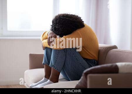 Jeune femme noire avec la dépression pleurant sur le canapé à la maison Banque D'Images