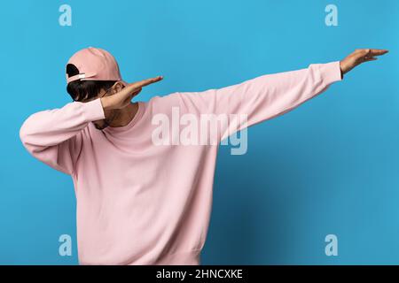 Un gars millénaire en sweat-shirt rose et en casquette sur fond bleu Banque D'Images