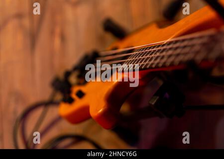 Une guitare basse électrique basée sur un stand placé sur la scène. Le sujet est éclairé par une lumière de scène lumineuse. Faible profondeur de champ, sujet inten Banque D'Images