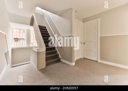 Long escalier avec marches grises et balustrades blanches dans un couloir lumineux et spacieux de l'appartement moderne à la maison Banque D'Images