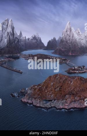 De dessus vue aérienne de l'eau calme de l'île de lavage de mer avec un village et des formations rocheuses couvertes de neige sous ciel nuageux dans la plage de Vik à Lofote Banque D'Images