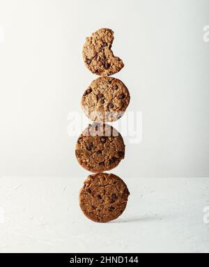 Délicieux biscuits sucrés avec des copeaux de chocolat empilés les uns sur les autres sur une table sur fond blanc dans la cuisine légère Banque D'Images