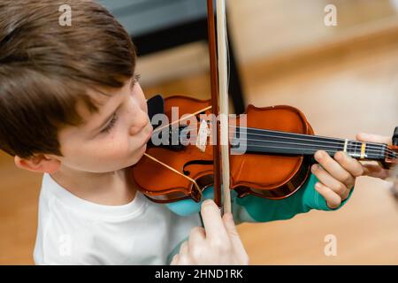 De dessus de l'adorable enfant jouant du violon avec l'arc tout en étudiant dans l'école de musique Banque D'Images