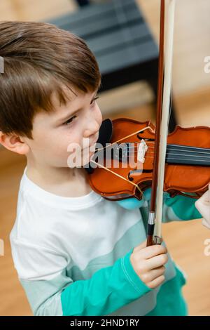 De dessus de l'adorable enfant souriant jouant du violon avec l'arc tout en étudiant dans l'école de musique Banque D'Images
