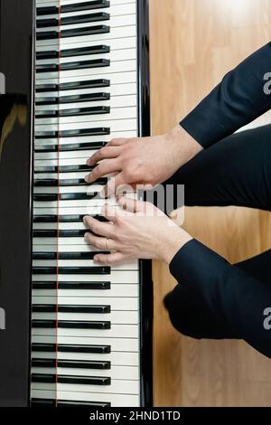 Vue de dessus de Crop un musicien masculin méconnaissable jouant de la mélodie sur le clavier du piano pendant la leçon dans une école de musique moderne Banque D'Images