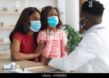 Fille malade et mère dans le visage masques médecin de visite Banque D'Images