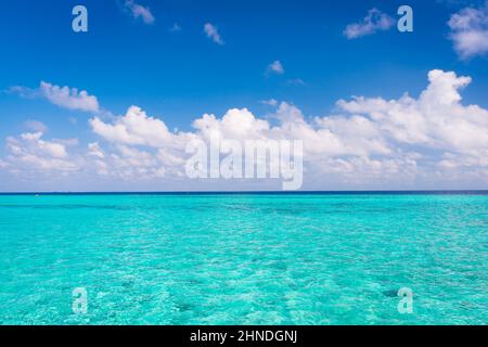Un voyage pour l'été. L'eau de la lagune est turquoise. Nuages blancs clairs dans le ciel bleu d'été. Maldives. Océan Indien. Banque D'Images