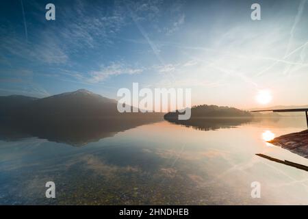 Coucher de soleil. Lac Zug en Suisse. Le sommet de la montagne de Rigi se reflète dans l'eau. Cailloux dans de l'eau claire. Banque D'Images