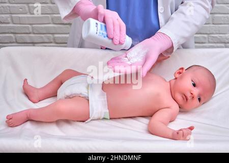 Le médecin verse de la poudre pour le nouveau-né.Infirmière dermatologue en uniforme Banque D'Images