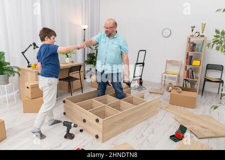 Papa et son fils font un geste de tortue tout en assemblant des meubles. Banque D'Images