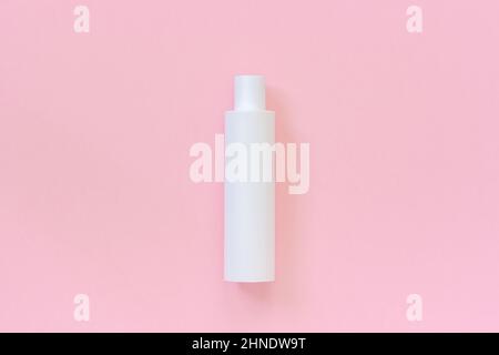 Une bouteille en plastique blanc vierge pour shampooing, lotion, crème ou autre produit cosmétique sur fond rose. Modèle ou maquette pour votre conception. Banque D'Images