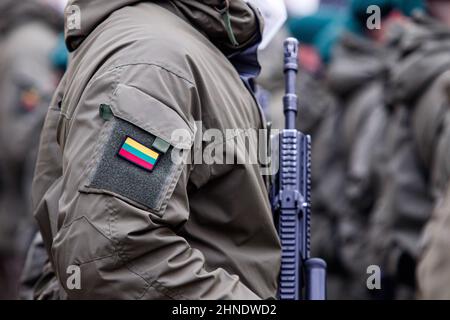 Soldat lituanien de l'OTAN tenant une arme. Gros plan du drapeau de la Lituanie sur l'uniforme de soldat. Conflit entre l'Ukraine et la Russie. Banque D'Images