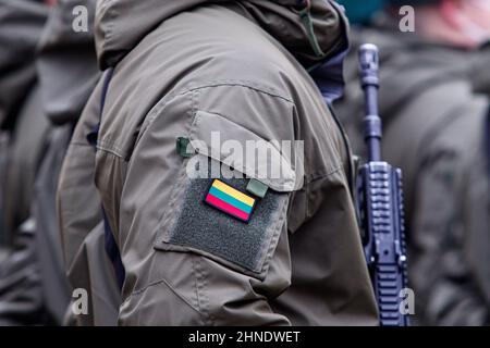 Soldat lituanien de l'OTAN tenant une arme. Gros plan du drapeau de la Lituanie sur l'uniforme de soldat Banque D'Images