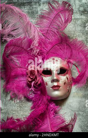 Masque de carnaval fait main à venise. Le masque est fait de papier mâché et représente le visage d'une femme, est de couleur rose et décoré de plumes. Banque D'Images