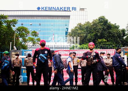 Jakarta, Indonésie. 16th févr. 2022. Les manifestants se rassemblent devant les bureaux du travail de Jakarta, tandis que les bureaux de police gardent la garde en arrière-plan. Les membres de la Confédération des syndicats indonésiens (KSPI) manifestent en demandant l'abrogation du règlement sur le programme de sécurité de la vieillesse (JHT) et la révocation du ministre du travail, Ida Fauziyahat, à l'extérieur du ministère indonésien de la main-d'oeuvre de Jakarta. Crédit : SOPA Images Limited/Alamy Live News Banque D'Images