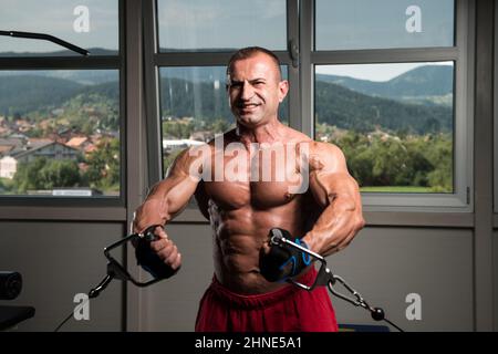 Bodybuilder travaille sur sa poitrine avec Cable Crossover In Gym Banque D'Images