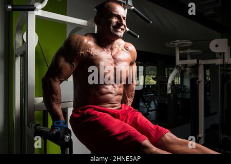 Remise en forme musculaire carrossier Poids lourd faisant l'exercice pour les triceps et poitrine sur barres parallèles dans la salle de sport Banque D'Images