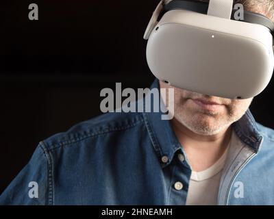 Homme habillé de façon décontractée portant un casque de réalité virtuelle Banque D'Images