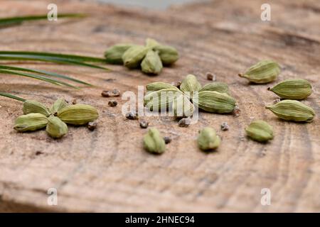 gros plan sur le bouquet de cardamome mûr vert avec des feuilles vertes sur fond en bois hors foyer. Banque D'Images