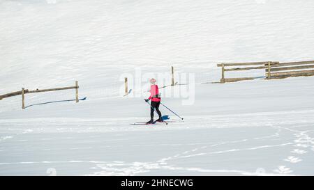 Une femme d'âge moyen, une skieuse sportive de fond, fait du ski sur la piste de ski vide de la montagne. Banque D'Images