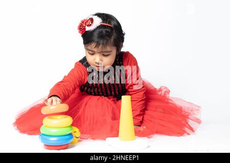 Fille indienne asiatique jouant avec des blocs de superposition avec des formes de tri isolées sur fond blanc. Amusement, activité, pré-école, éducation, maternelle, Banque D'Images