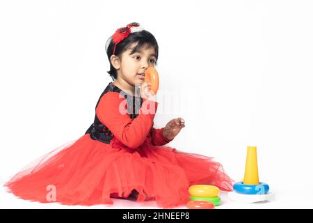 Fille indienne asiatique jouant avec des blocs de superposition avec des formes de tri isolées sur fond blanc. Amusement, activité, pré-école, éducation, maternelle, Banque D'Images