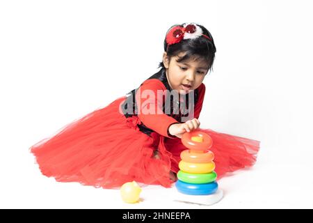 Fille indienne asiatique jouant avec des blocs de superposition avec des formes de tri isolées sur fond blanc. Amusement, activité, pré-école, éducation, maternelle, Banque D'Images