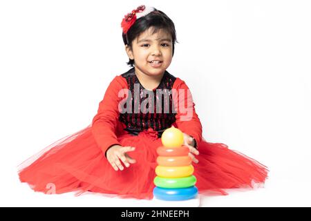 Fille indienne asiatique jouant avec des blocs de superposition avec des formes de tri isolées sur fond blanc. Amusement, activité, pré-école, éducation, maternelle, Banque D'Images