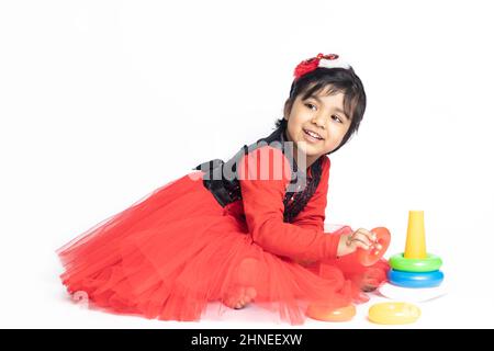 Fille indienne asiatique jouant avec des blocs de superposition avec des formes de tri isolées sur fond blanc. Amusement, activité, pré-école, éducation, maternelle, Banque D'Images