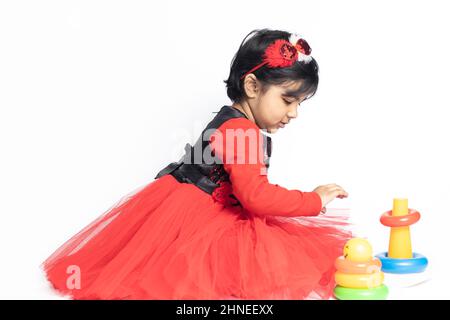 Fille indienne asiatique jouant avec des blocs de superposition avec des formes de tri isolées sur fond blanc. Amusement, activité, pré-école, éducation, maternelle, Banque D'Images