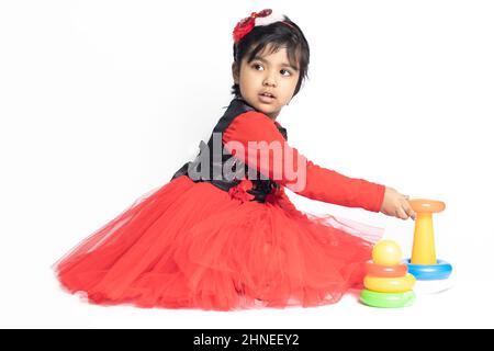 Fille indienne asiatique jouant avec des blocs de superposition avec des formes de tri isolées sur fond blanc. Amusement, activité, pré-école, éducation, maternelle, Banque D'Images